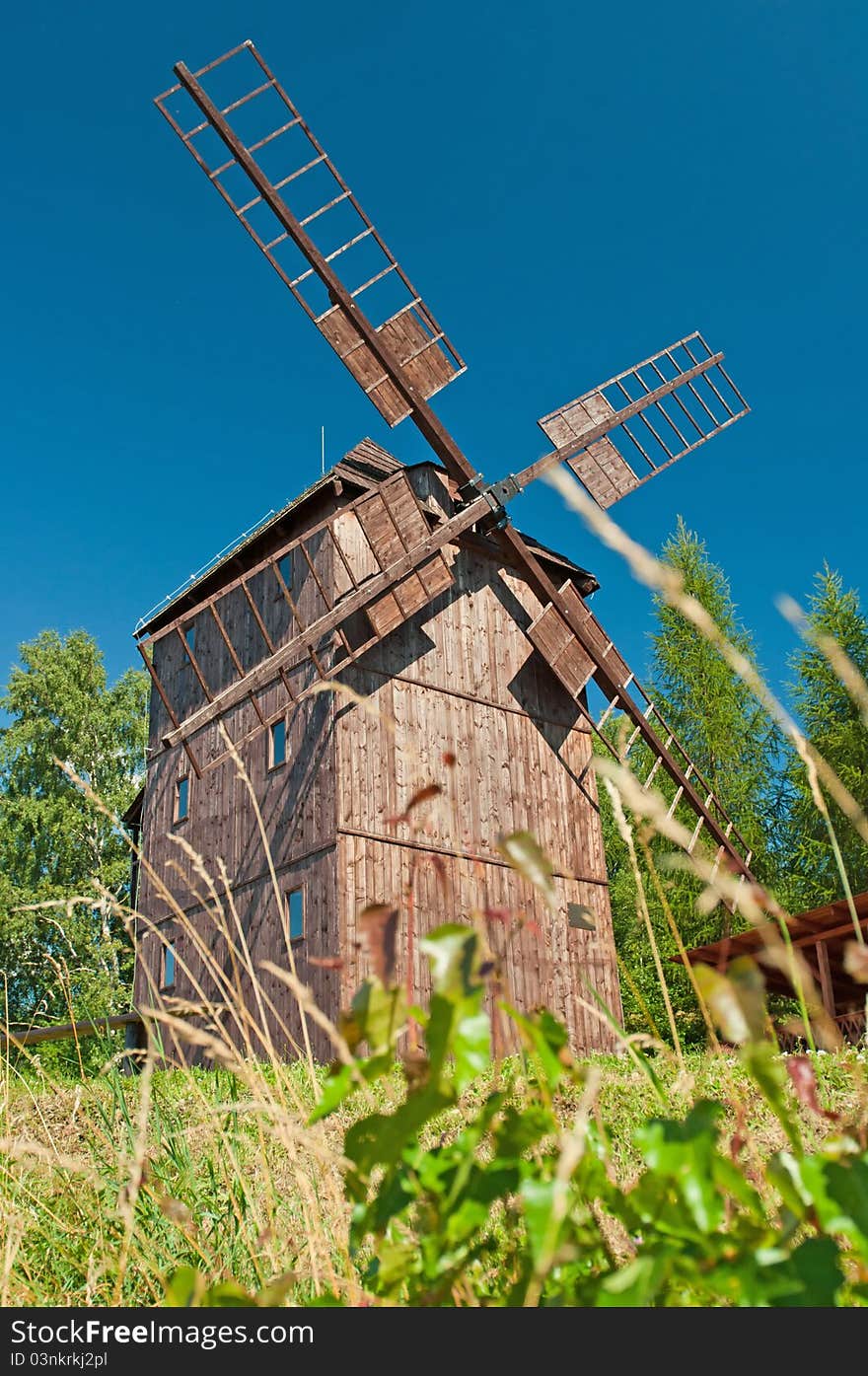 Old traditional wooden windmill hidden in forest.