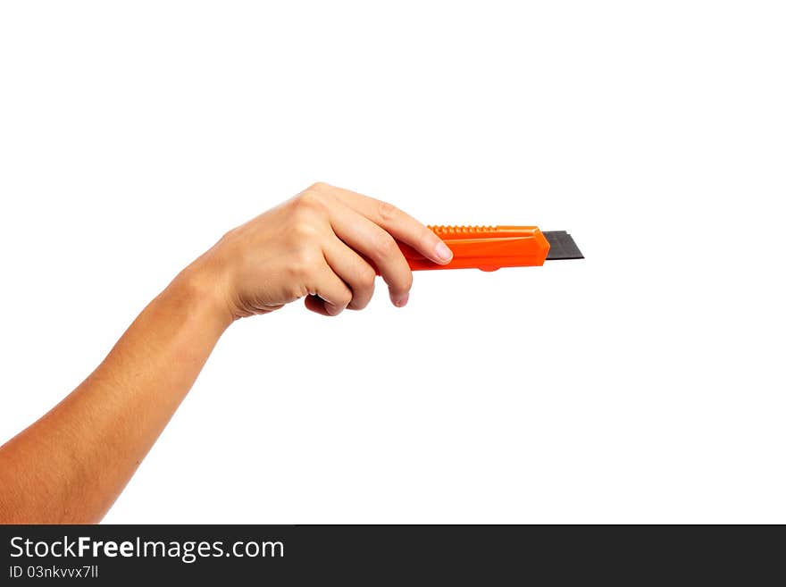 A female hand holding an orange craft knife on an isolated white background. A female hand holding an orange craft knife on an isolated white background