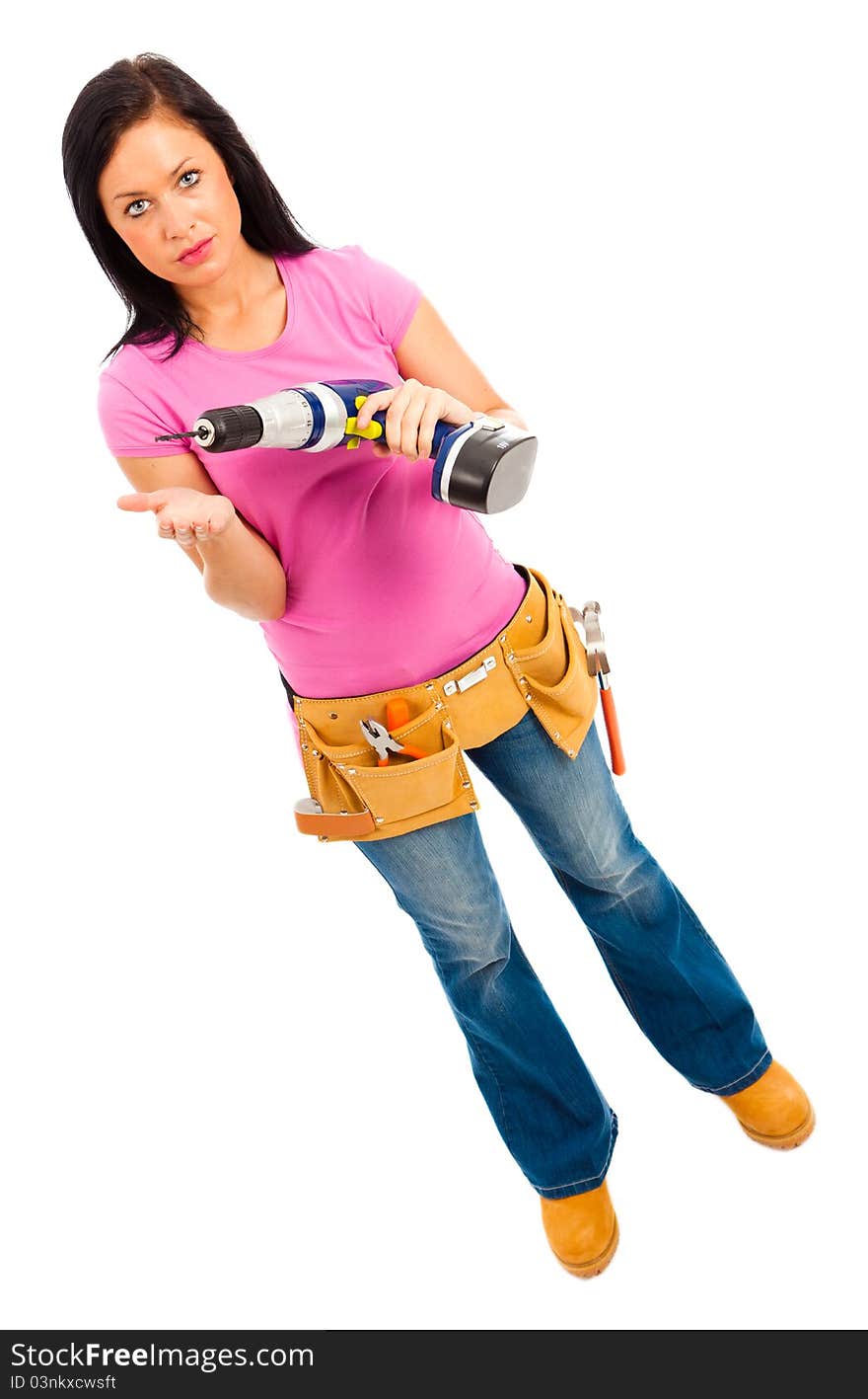 A young female wearing pink top blue jeans and tool belt holding an electric drill on isolated white background. A young female wearing pink top blue jeans and tool belt holding an electric drill on isolated white background