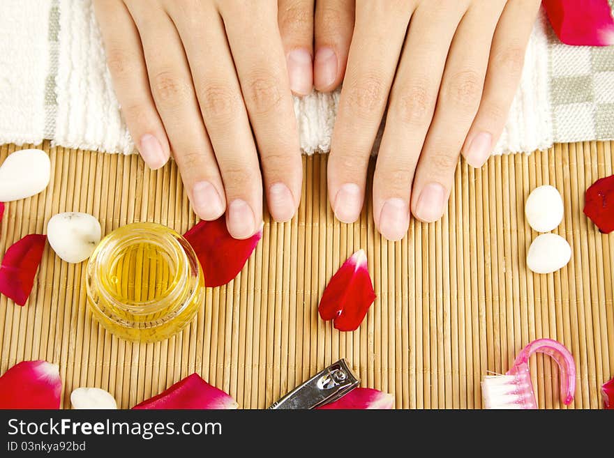 Close-up of girl lying on hand towel next to the cream, rose petals and manicure equipment. Close-up of girl lying on hand towel next to the cream, rose petals and manicure equipment