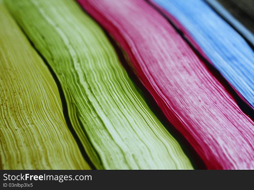 Colored paint streaks on glass with light shining from behind.