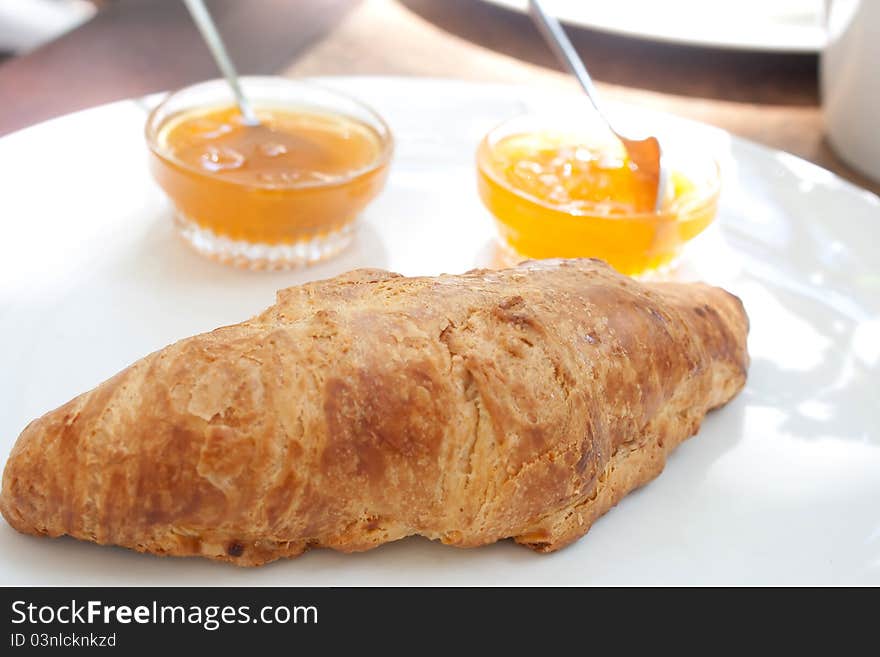 Large croissant on a plate with a portion of jam