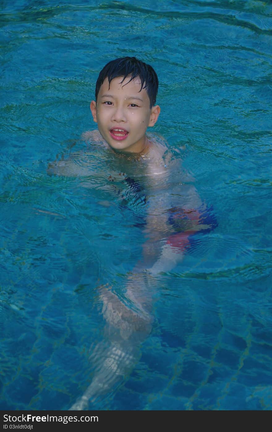 A happy child to swim in the blue water of the pool by a hot summer day. A happy child to swim in the blue water of the pool by a hot summer day