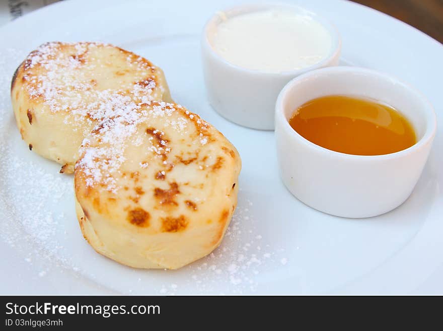 Russian desert named syrniki (quark cheese pancakes) with sour cream and honey