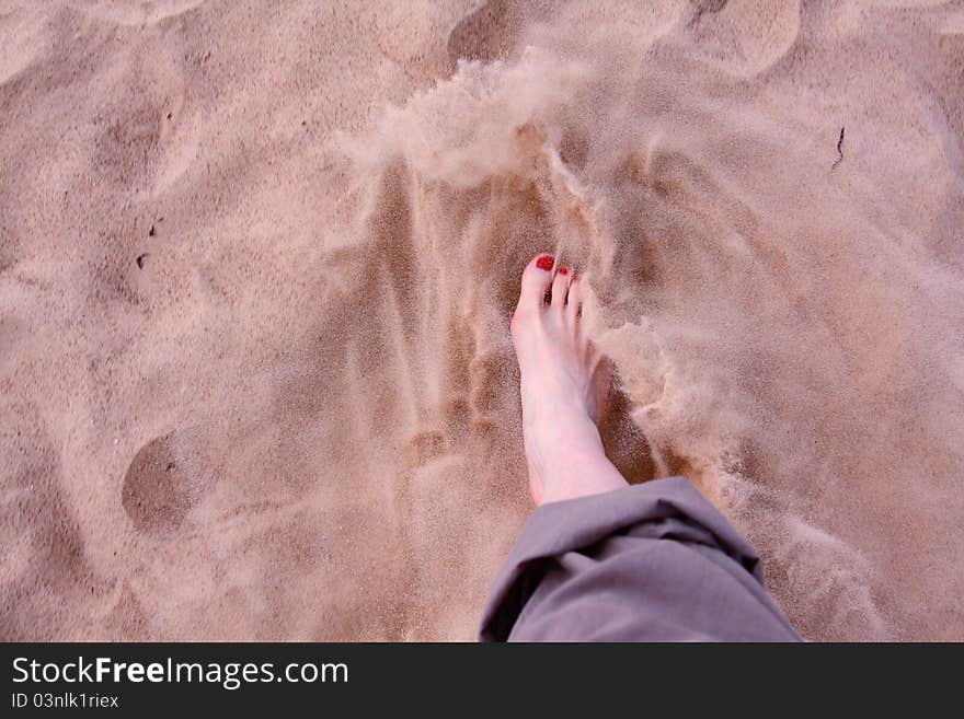 A woman's foot in soft sand on a beach