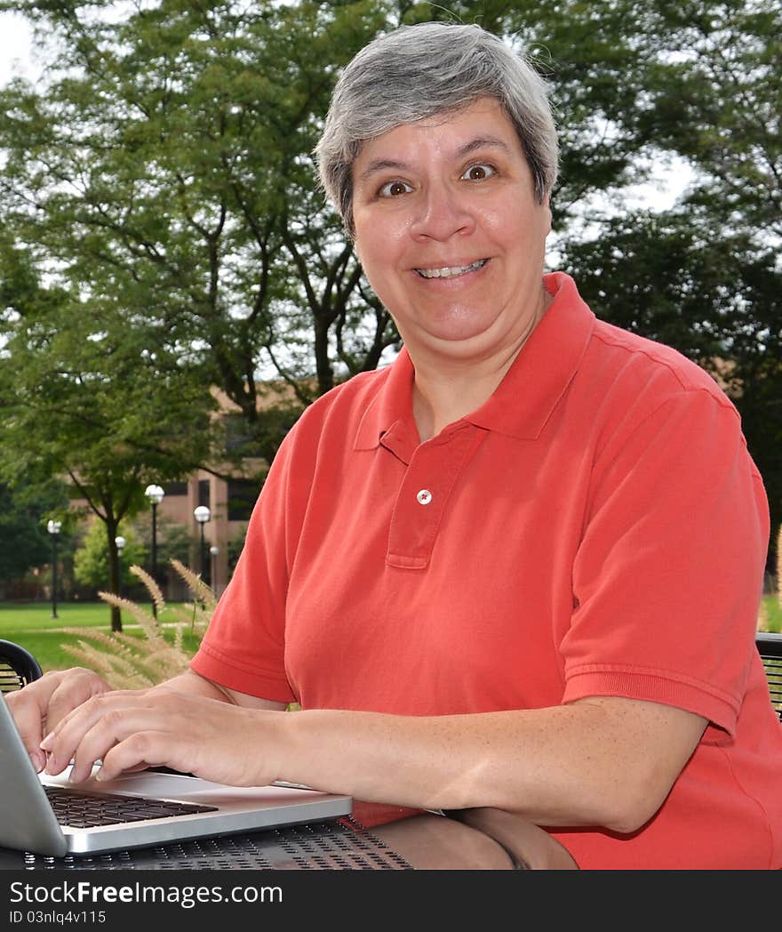 Happy middle-aged woman at table with laptop. Happy middle-aged woman at table with laptop