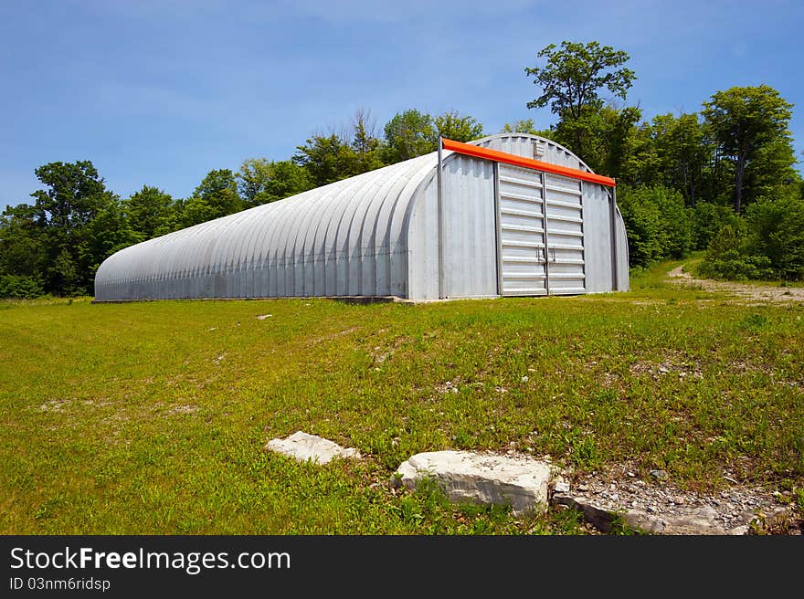 Wide angle image of a huge steel warehouse on the edge of a forest. Wide angle image of a huge steel warehouse on the edge of a forest.