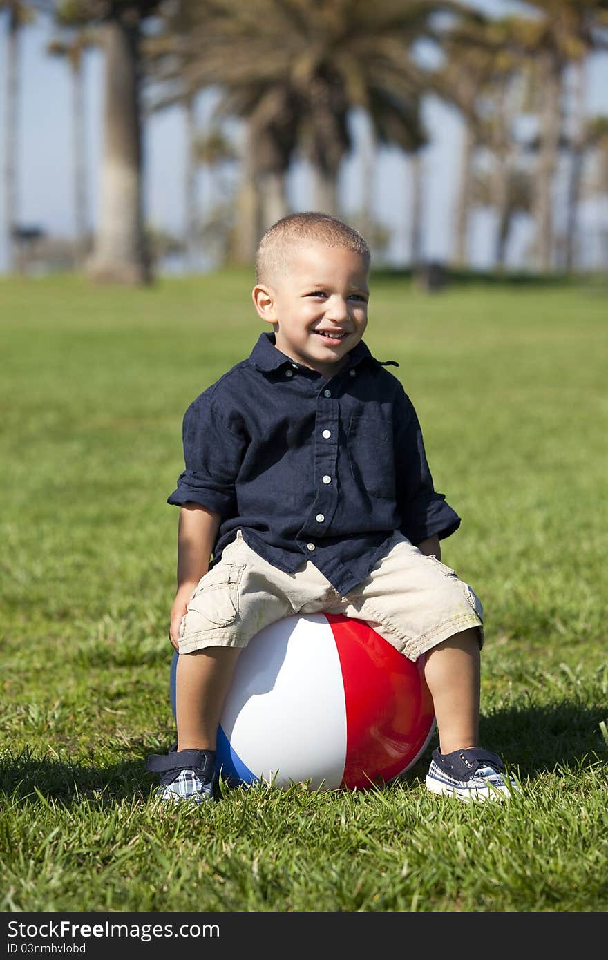 Little boy sitting on a beach ball at the park. Little boy sitting on a beach ball at the park