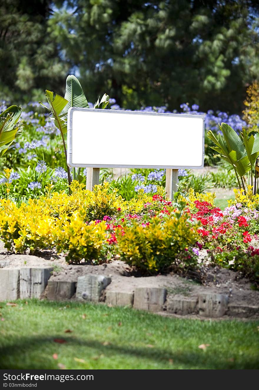 Empty white sign surrounded by flowers - room for copy. Empty white sign surrounded by flowers - room for copy