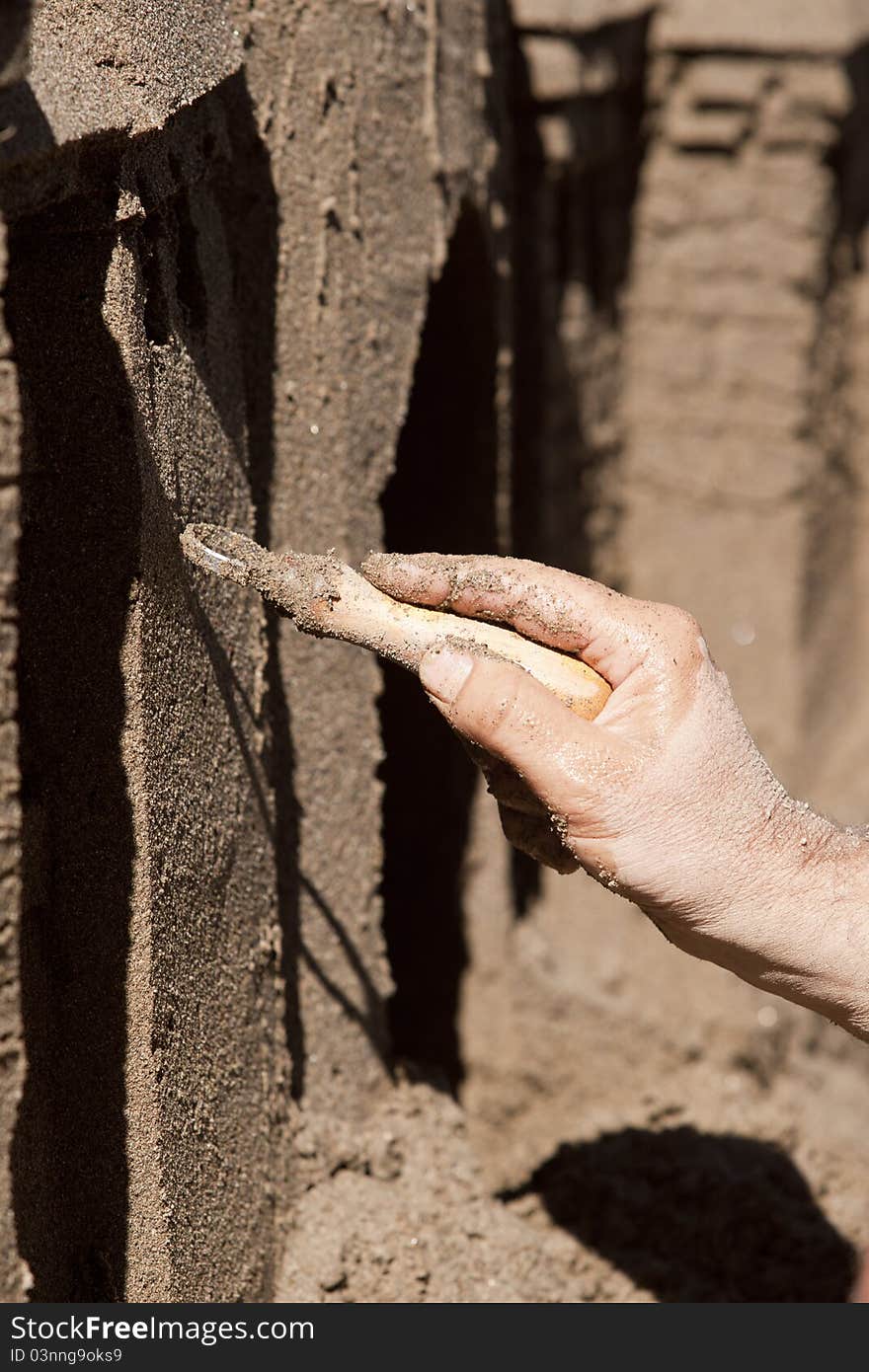 A steady hand shapes intricate features in a sand sculpture. A steady hand shapes intricate features in a sand sculpture.