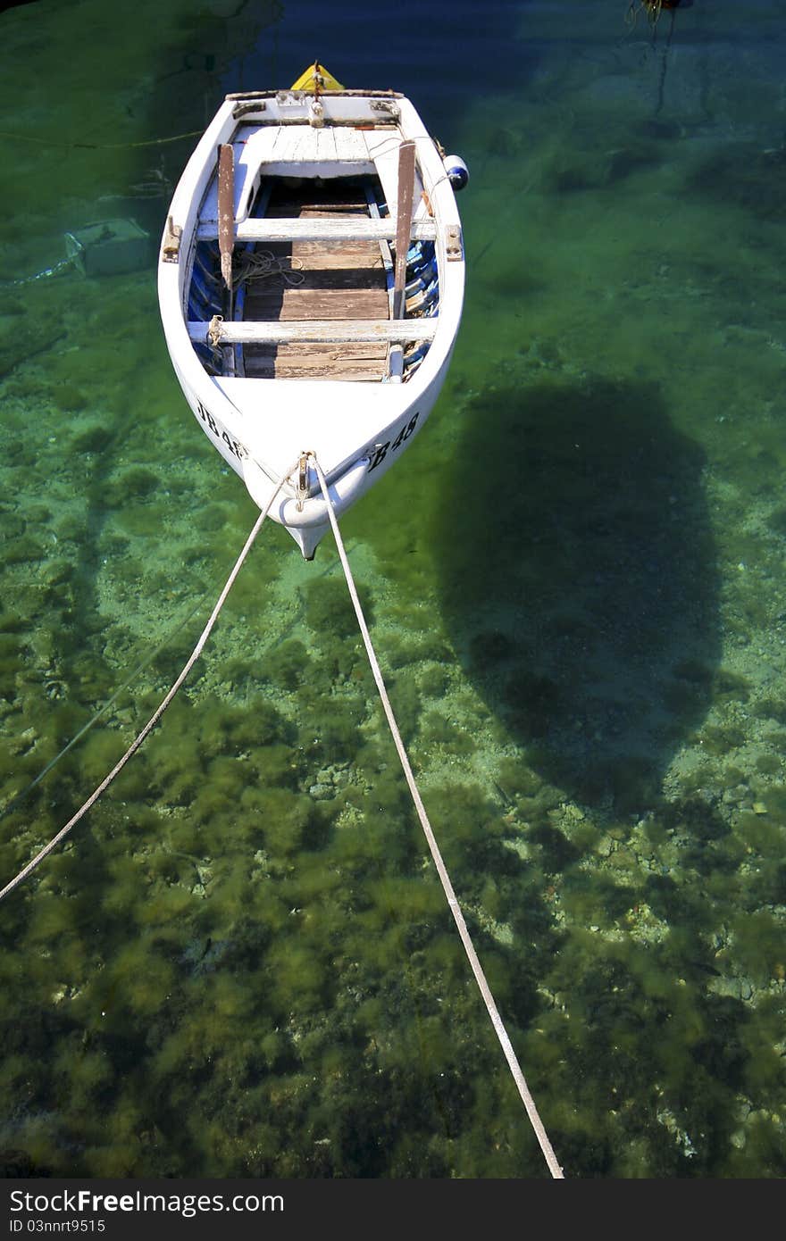 White berthed fishing boat on the emerald sea with the reflection on the seabed. White berthed fishing boat on the emerald sea with the reflection on the seabed