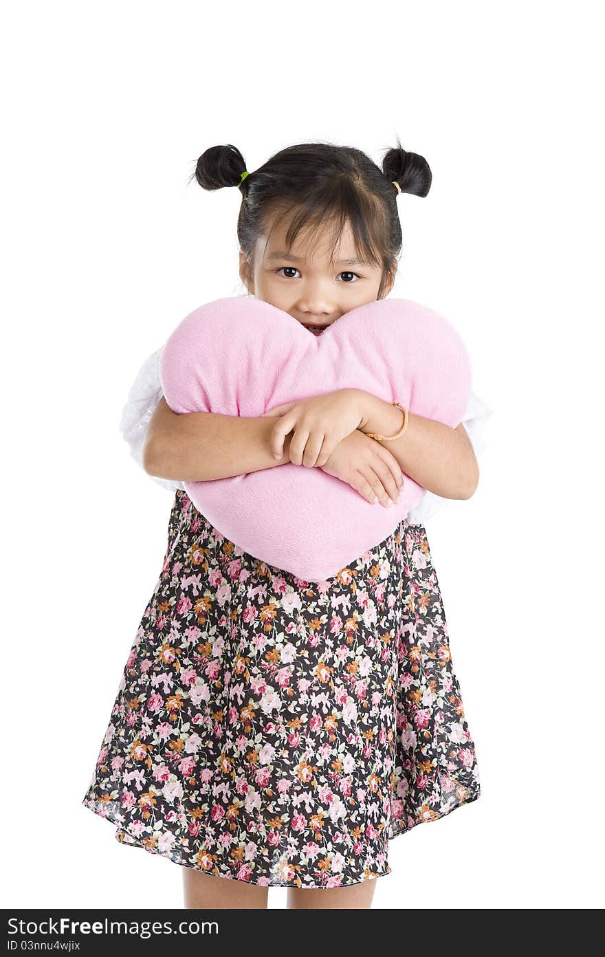 Pretty little girl with heart shaped pillow, isolated on white background