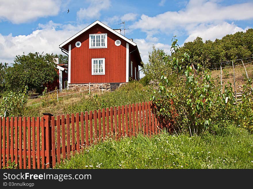 Red wooden house with red fence in front.