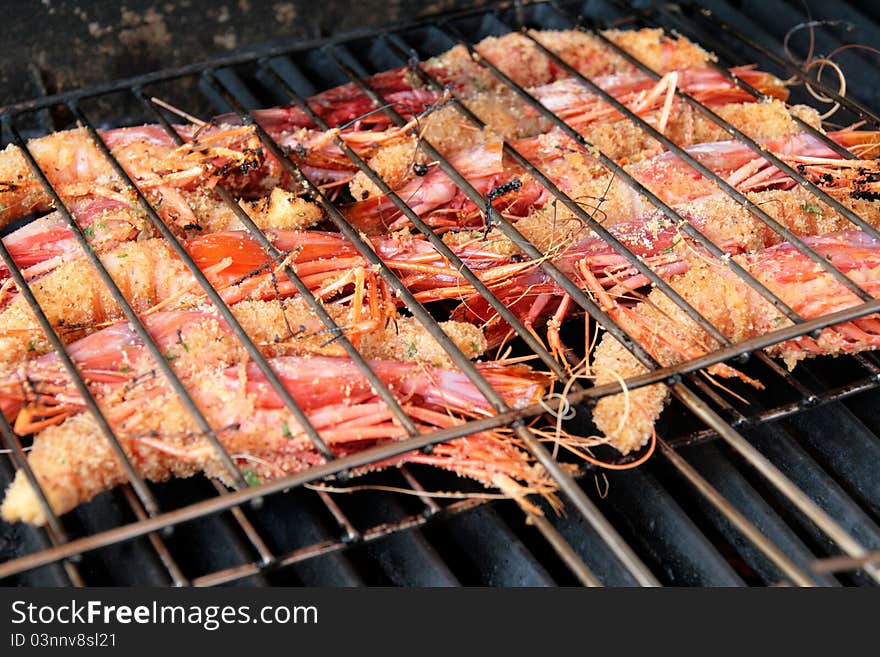 King prawns coated with breadcrumbs while cooking on a barbecue grill. King prawns coated with breadcrumbs while cooking on a barbecue grill