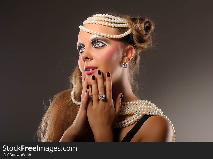 Beautiful fair-haired professionally made up girl with blue eyes wearing pearl beads and diamonds surprised. Beautiful fair-haired professionally made up girl with blue eyes wearing pearl beads and diamonds surprised