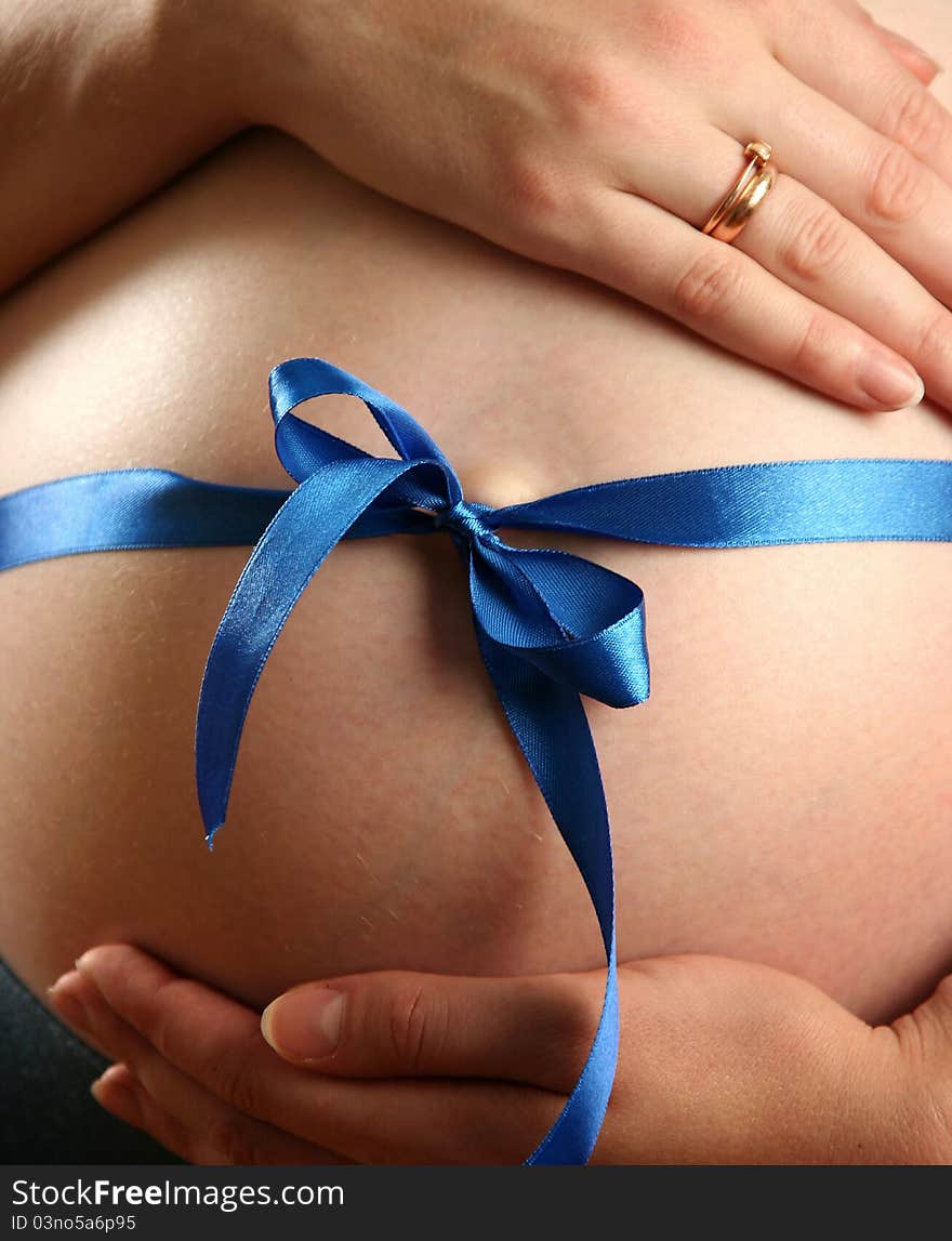 Pregnant woman with a blue bow on her belly. Pregnant woman with a blue bow on her belly