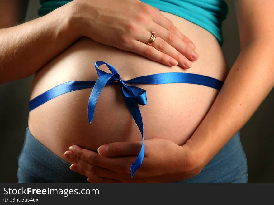 Pregnant woman with a blue bow on her belly. Pregnant woman with a blue bow on her belly