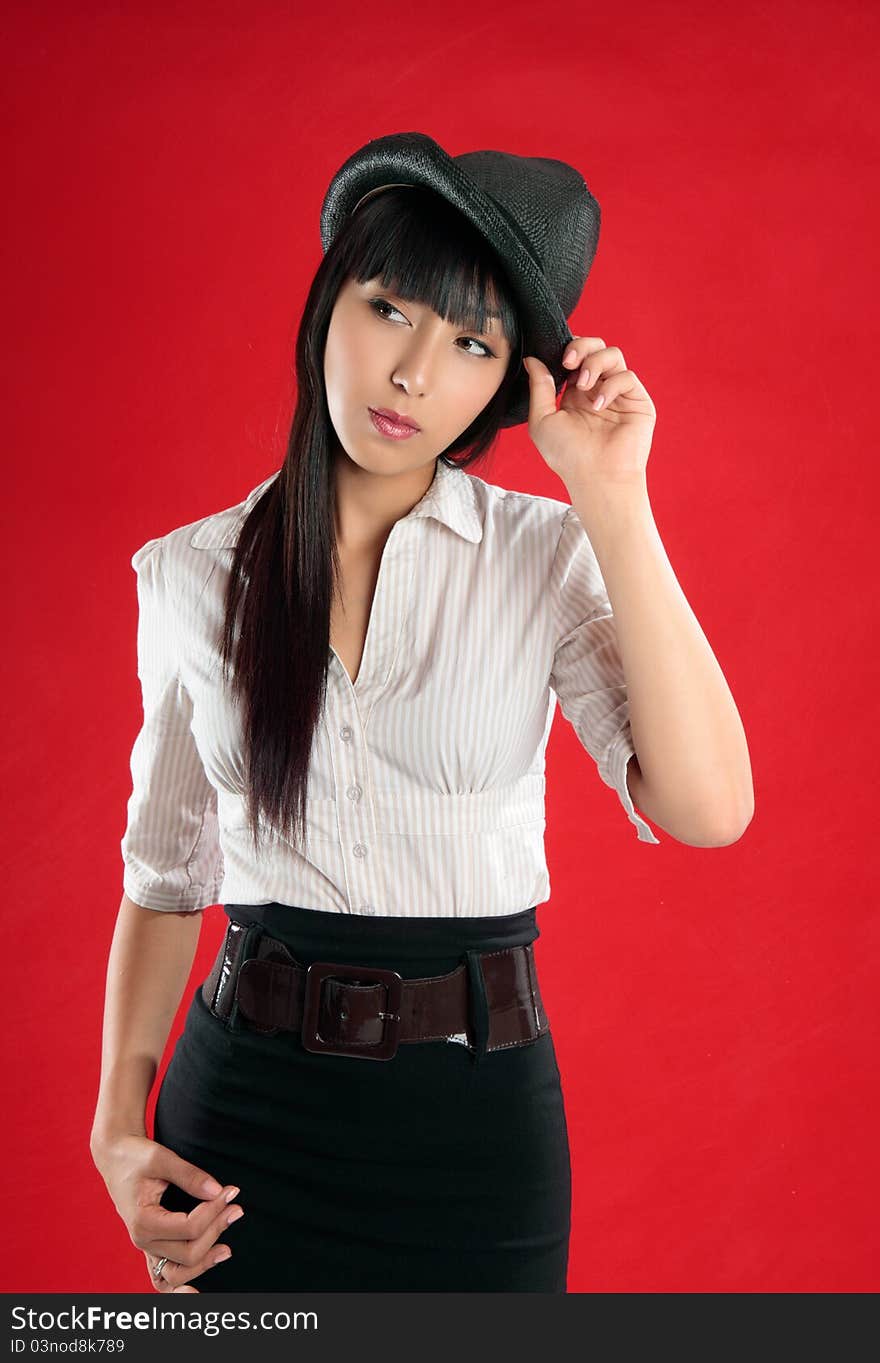 Young pretty woman wearing a beige white striped blouse, black skirt and hat.  She is looking sideways and is tilting her head slightly. Young pretty woman wearing a beige white striped blouse, black skirt and hat.  She is looking sideways and is tilting her head slightly.