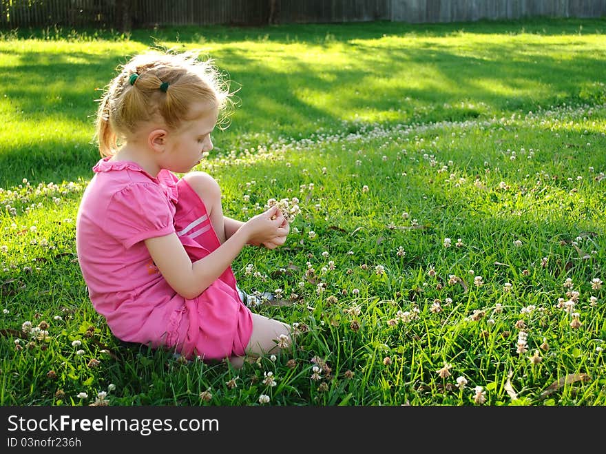 Young Girl In Pink Picking Up Flowers In A Field