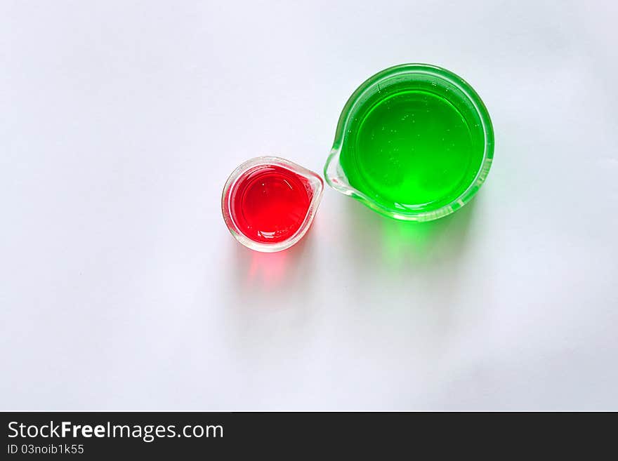 A two beakers contain red and green solution, top view