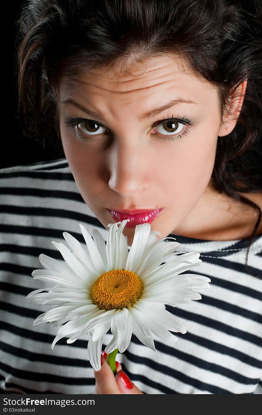 Beautiful young woman with chamomile in hand on black background