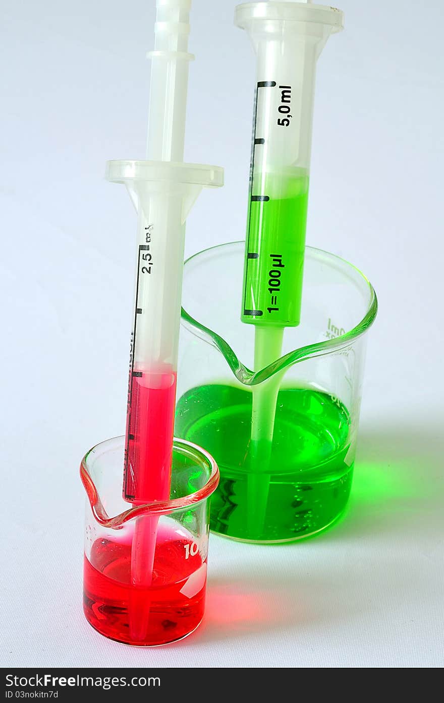 A two pipet in the beaker with red and green solution. A two pipet in the beaker with red and green solution