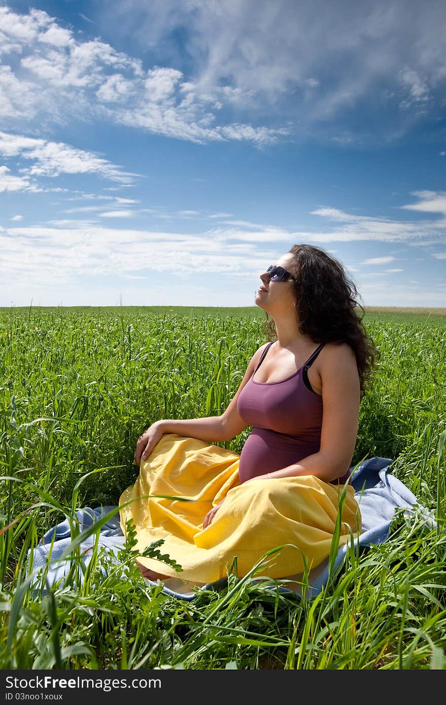 Pregnant woman on green grass field under blue sky