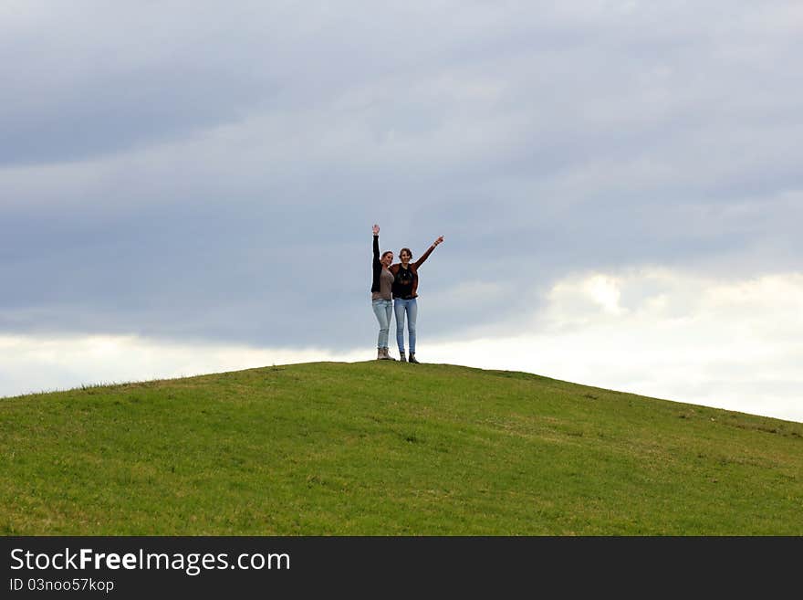 Two Women On Top Of Green Hill Waving