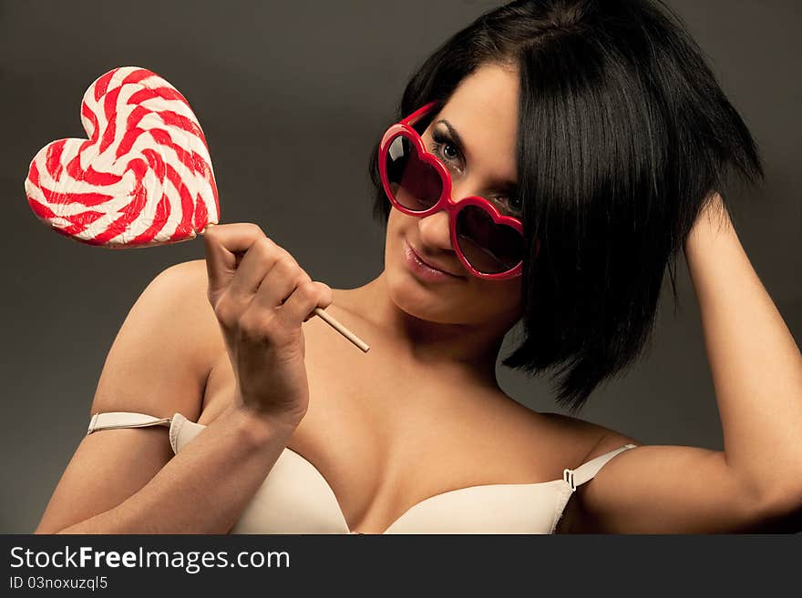 Young woman with heart shaped lollipop and sunglasses