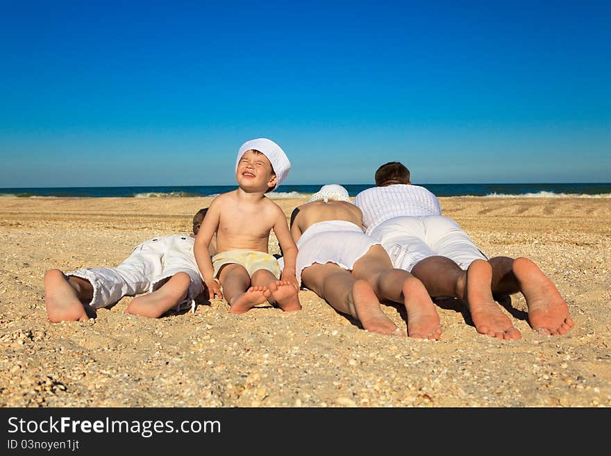 Photo of family lying on sand on background of blue sky