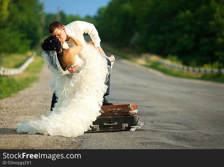 Newlywed couple kissing on a road