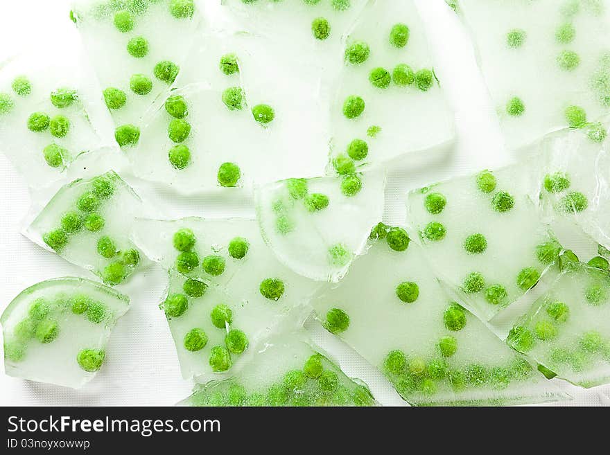 Green peas frozen in cracked and broken pieces of thick ice. Green peas frozen in cracked and broken pieces of thick ice