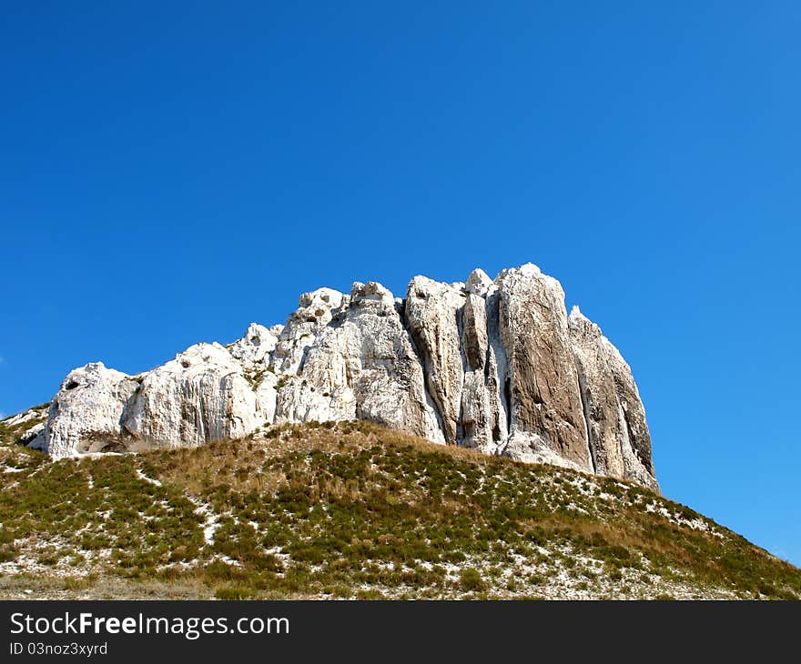 Photo of cretaceous rocky formation against the blue sky with clouds