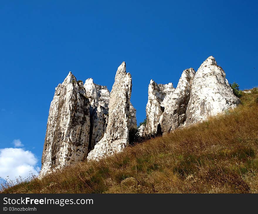 Photo of cretaceous rocky formation against the blue sky with clouds