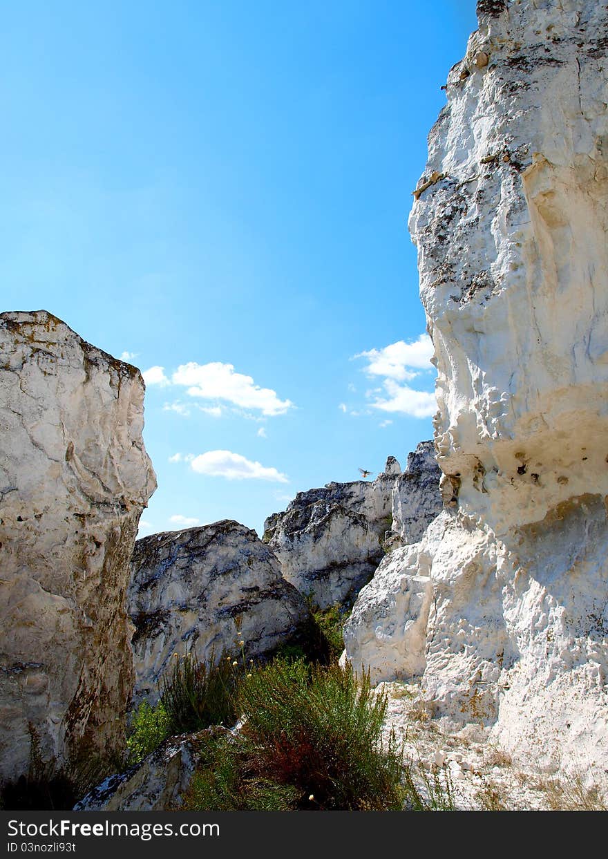 Photo of cretaceous rocky formation against the blue sky with clouds