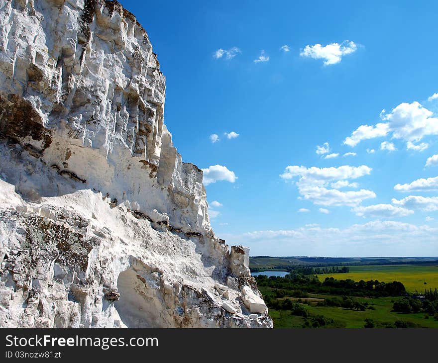 Photo of cretaceous rocky formation against the blue sky with clouds