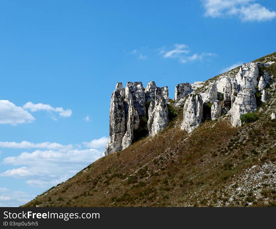 Photo of cretaceous rocky formation against the blue sky with clouds