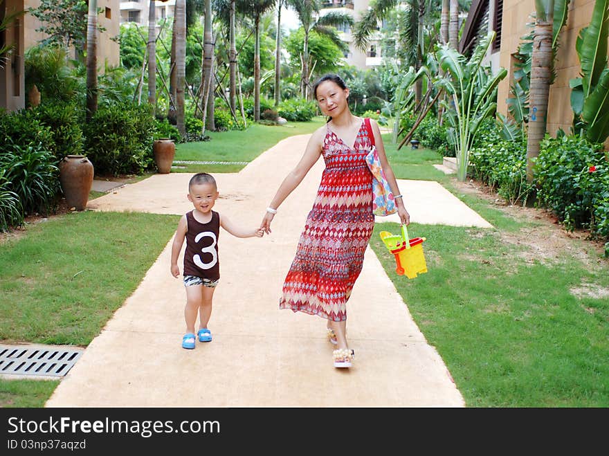 Asian young mother and son walk in tropical park. Asian young mother and son walk in tropical park