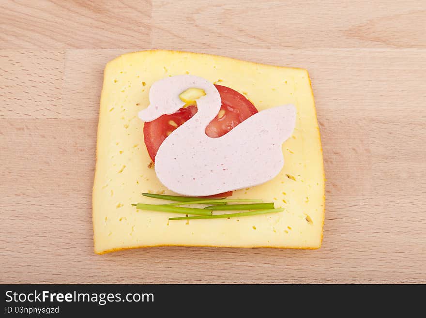 Studio-shot of a wooden board with a slice of healthy school bread for kids with mortadella and chesse,. garnished with chives,and tomato. Studio-shot of a wooden board with a slice of healthy school bread for kids with mortadella and chesse,. garnished with chives,and tomato.