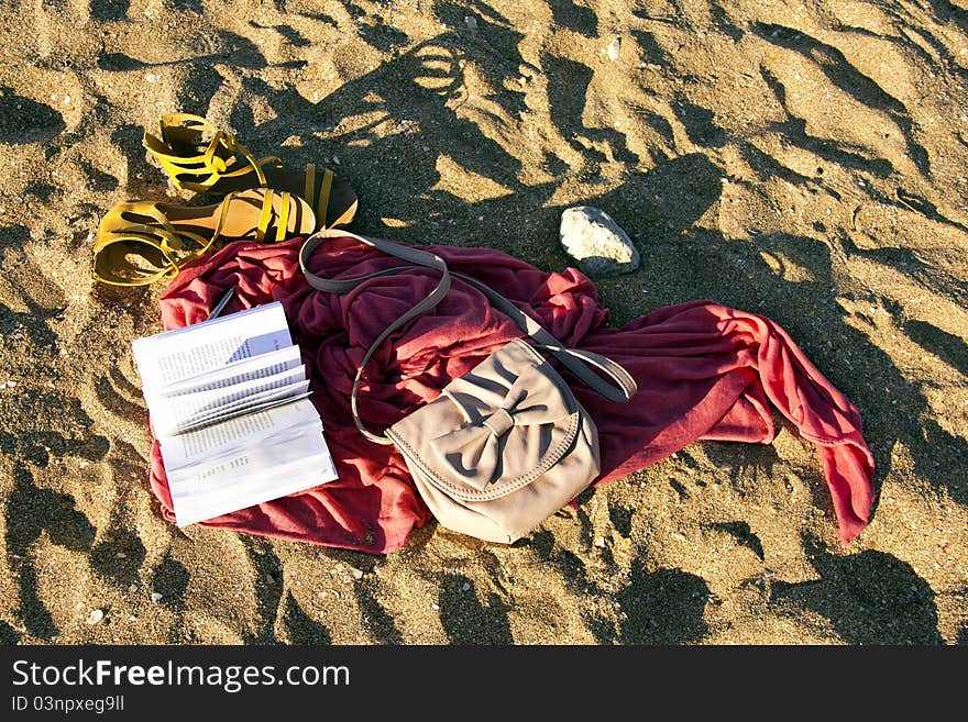 Sandals, book and pareos on the sand