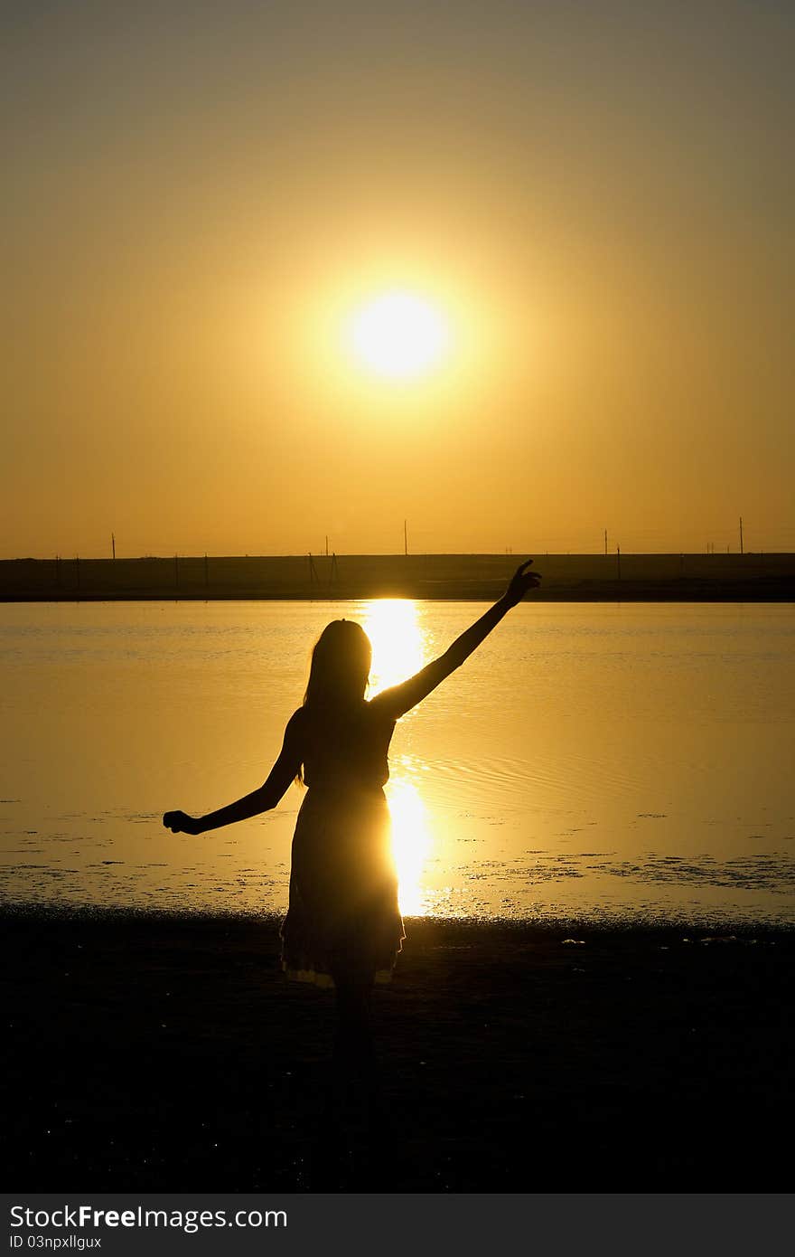 Silhouette of the dancing girl with sunset on the background