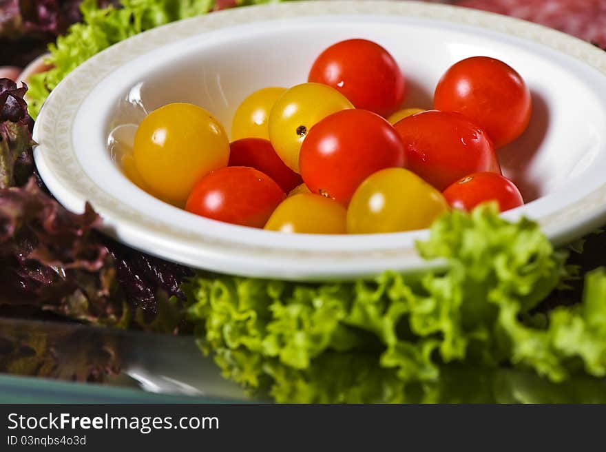 Cherry tomatoes on the plate with salad leaves