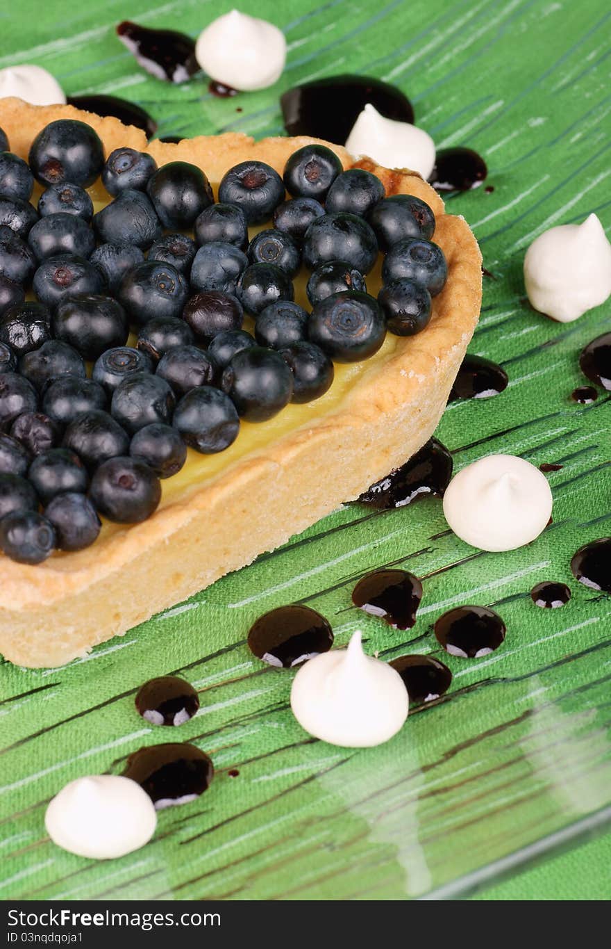 Heart-shaped tart with blueberries served on a glass dish decorated with meringues and topping. Selective focus, soft focus. Heart-shaped tart with blueberries served on a glass dish decorated with meringues and topping. Selective focus, soft focus