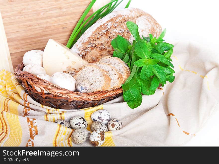 The wooden basket with mushrooms, bread, cheese, mint, quail eggs, and green onions. The wooden basket with mushrooms, bread, cheese, mint, quail eggs, and green onions