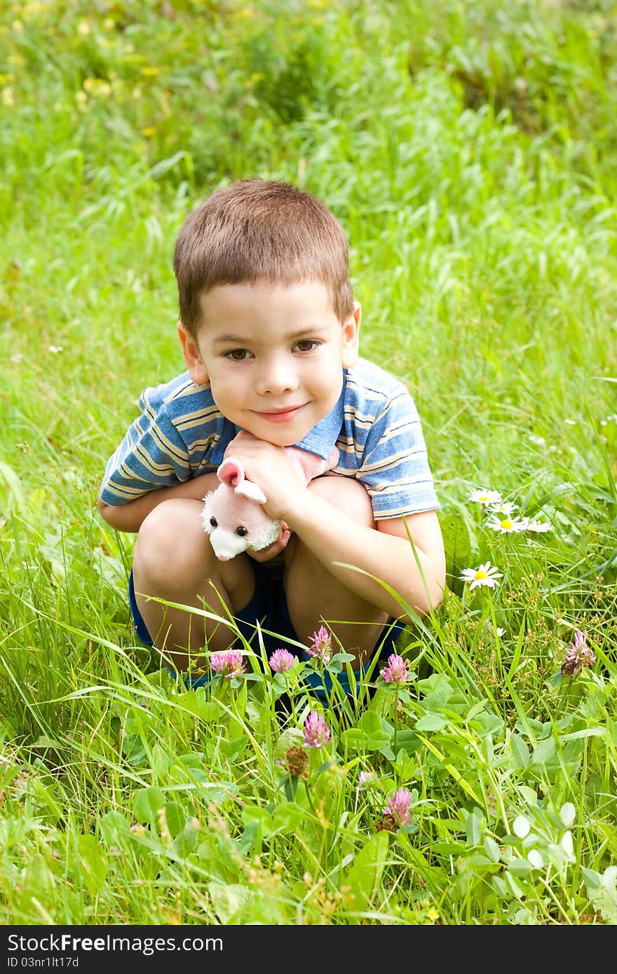 Happy little boy sitting on the grass in the park