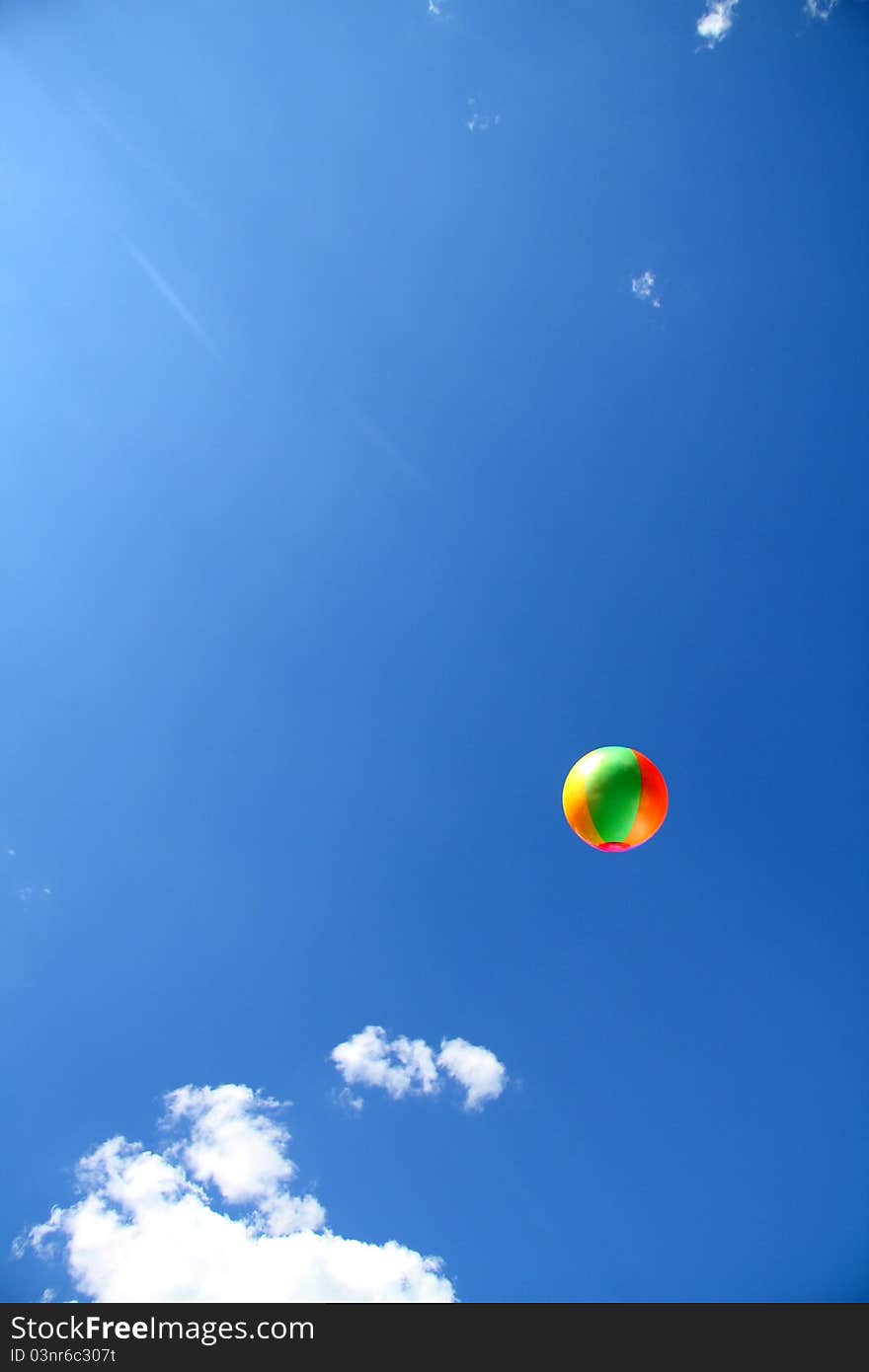 Beach ball thrown into a blue cloudy sky. Beach ball thrown into a blue cloudy sky