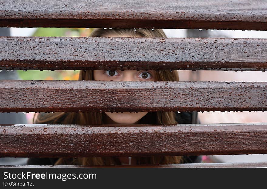 Teen girl looking through wet fence with water drops. Teen girl looking through wet fence with water drops