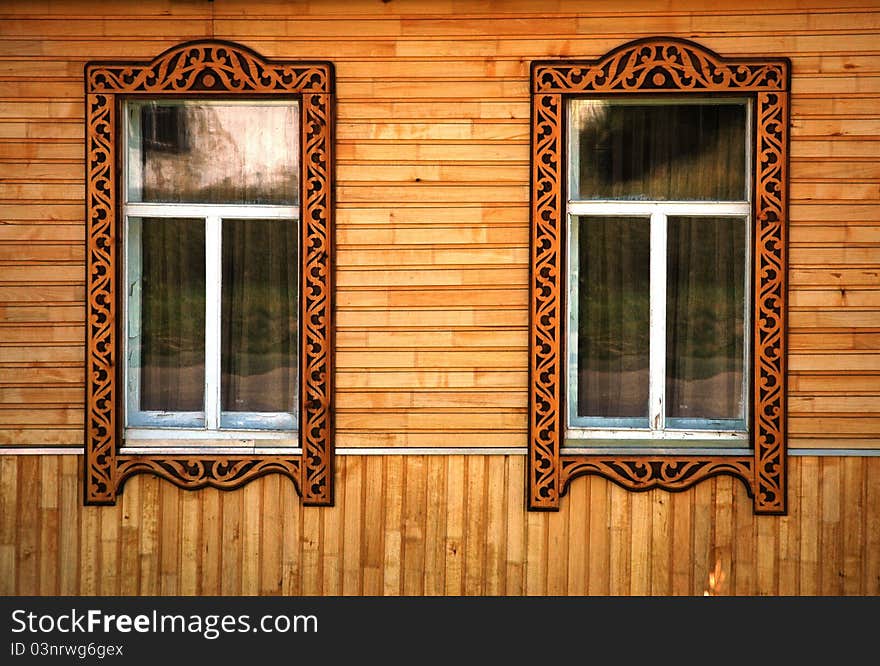 Two windows with wooden platbands. Тraditional Russian decoration.