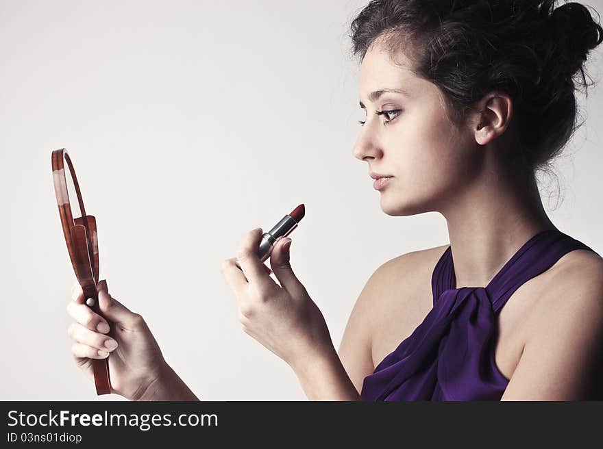 Beautiful woman putting on some lipstick. Beautiful woman putting on some lipstick