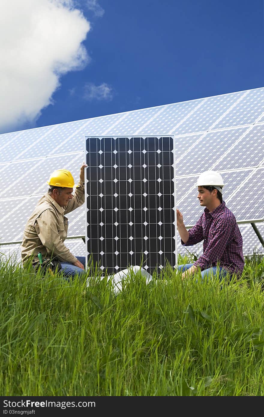 Technicians installing solar panels, low angle view